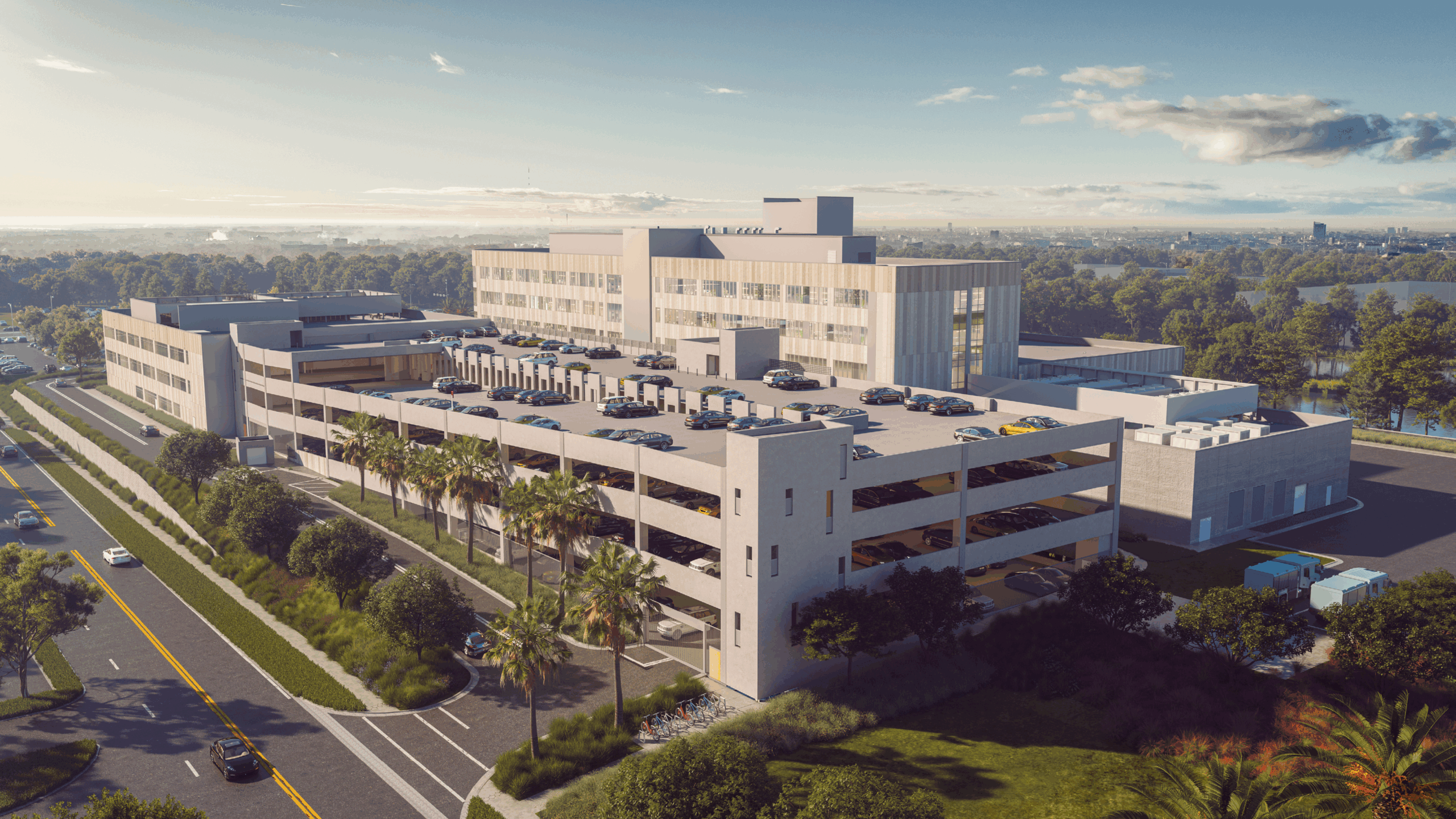 A multilevel parking garage attached to a building behind it surrounded by trees and roads.