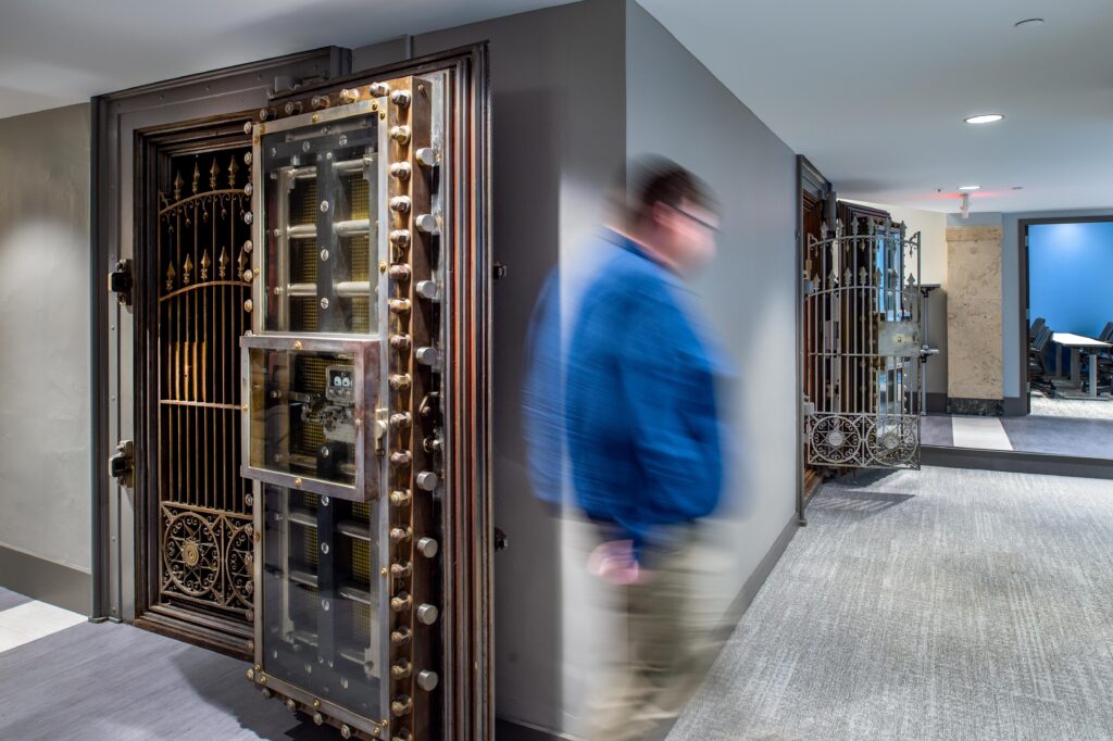 Photo of a man walking in a hallway in the BAMSL offices. A former bank vault has been adapted to office storage