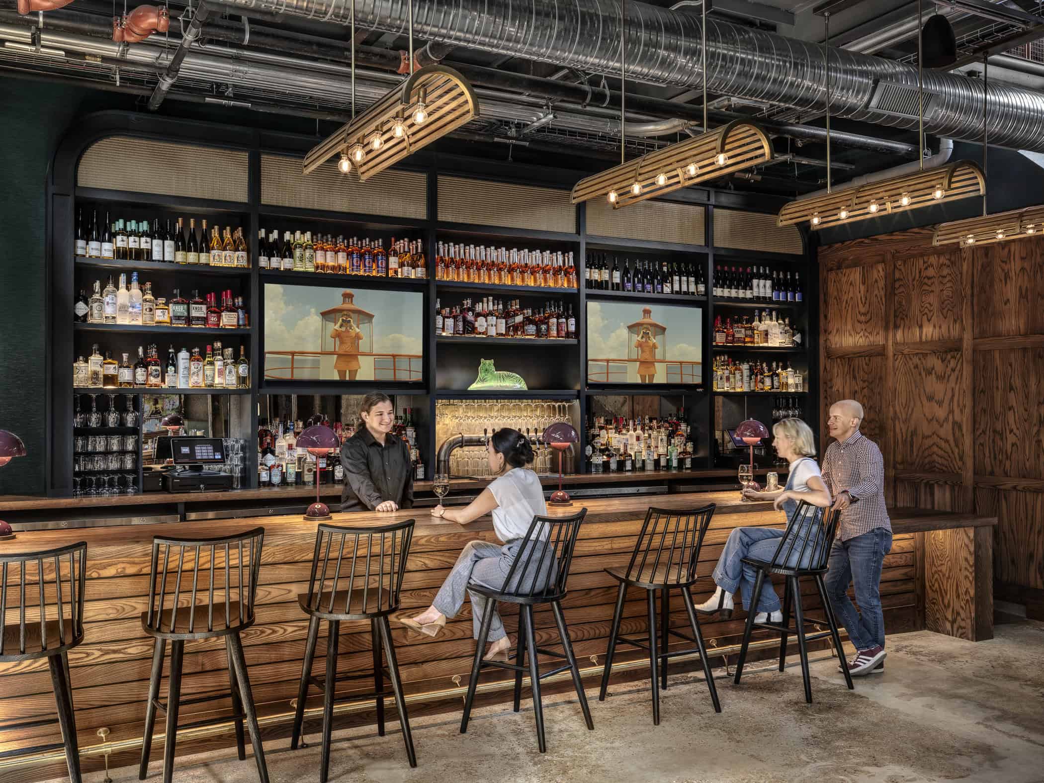 Multiple people drink at a well-stocked bar