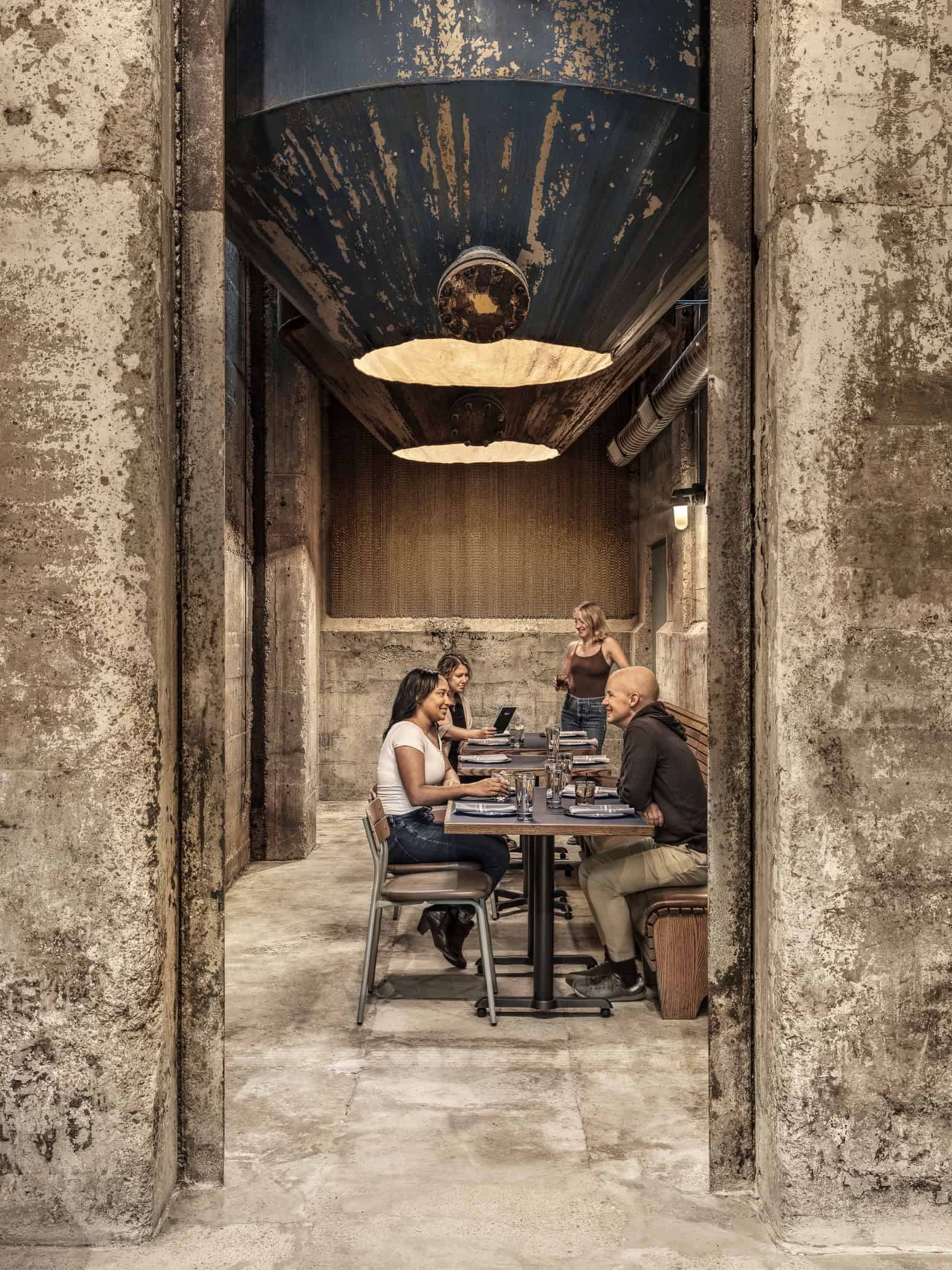 People sitting in a private dining area under restored mixing drums at Expat BBQ