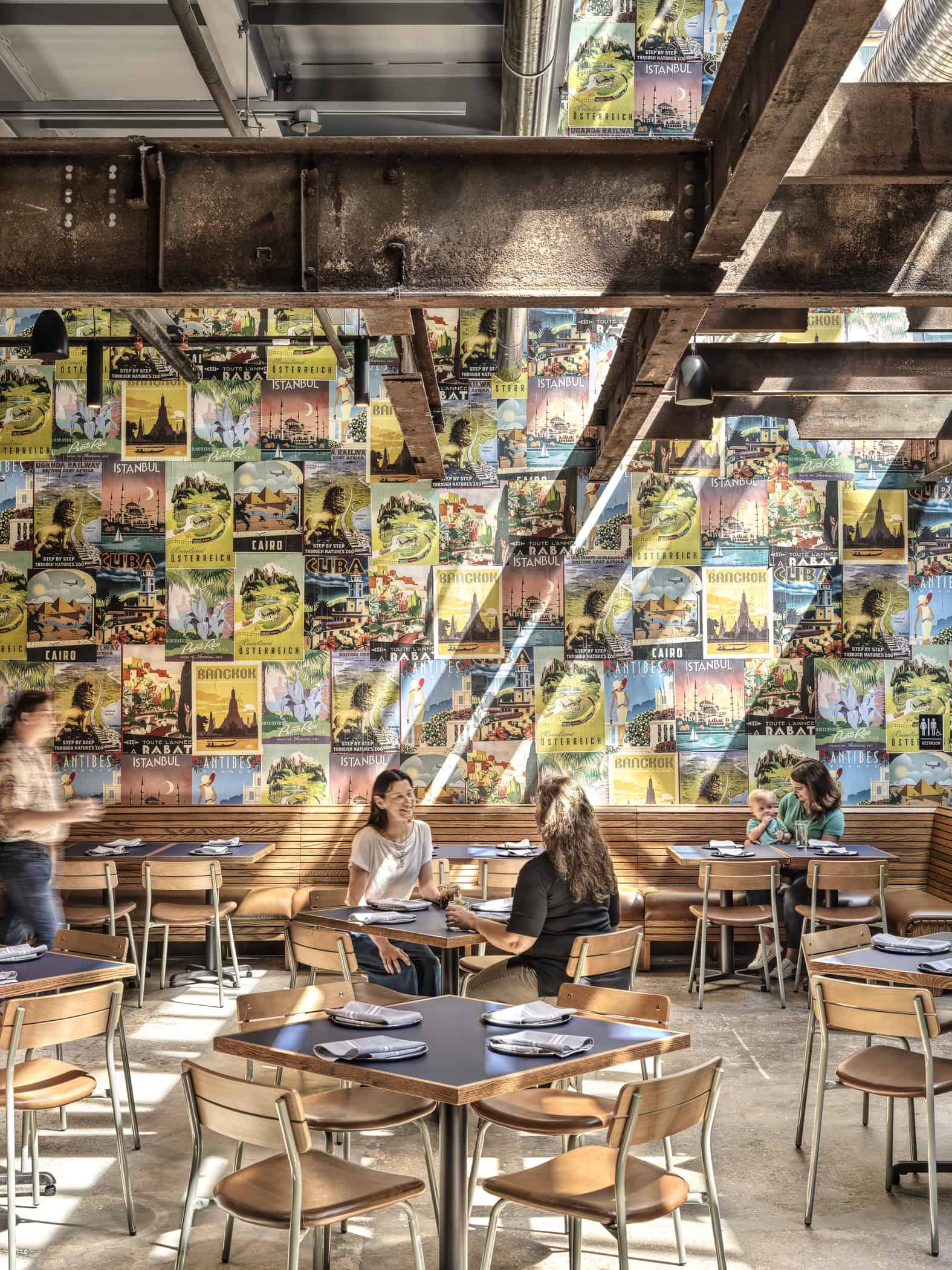 People sitting in the main dining area behind a wall of vintage travel posters at Expat BBQ