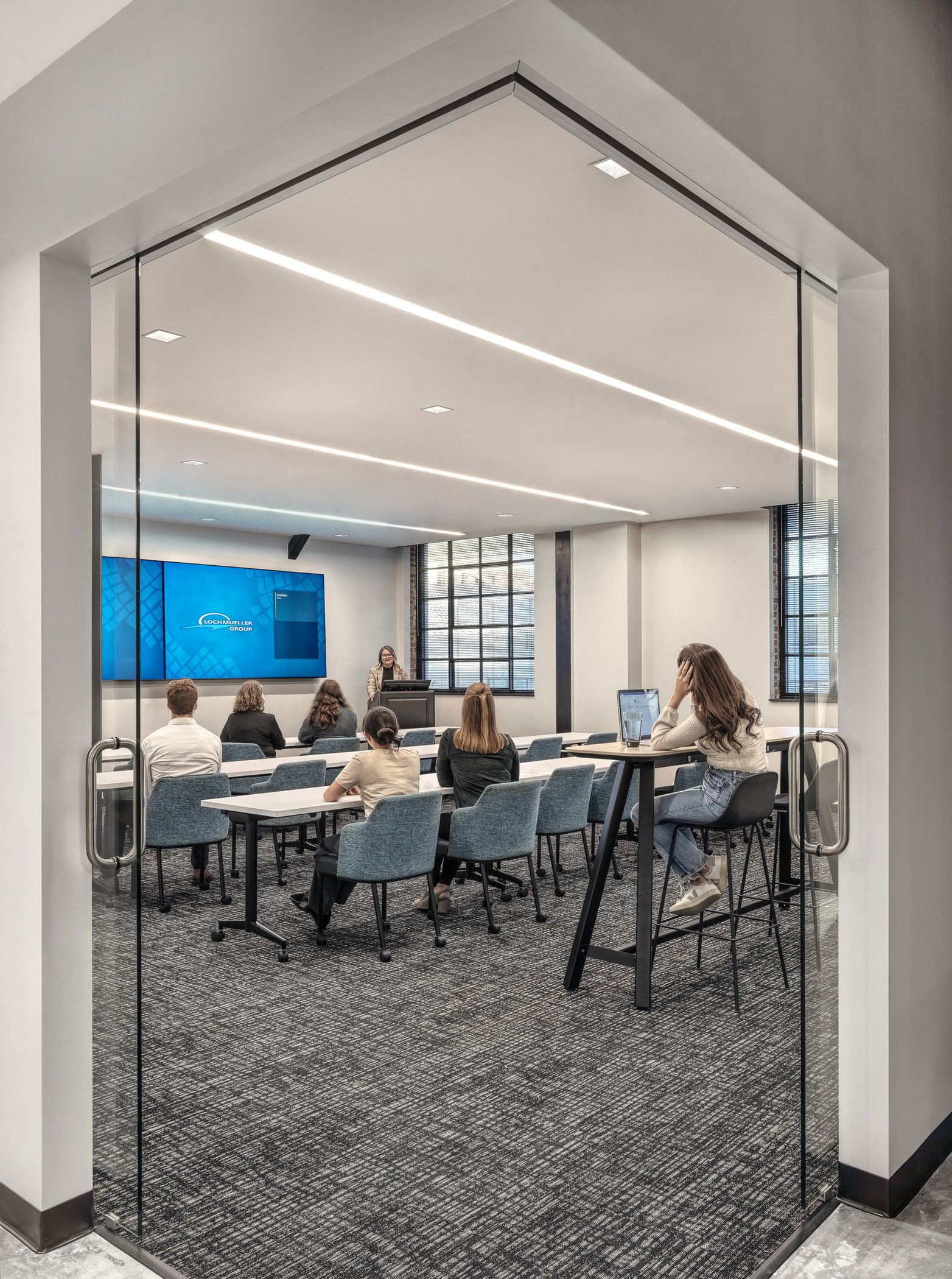 Training room with rows of chairs and desks in front of screens and presentation podium at the Lochmueller Group office.