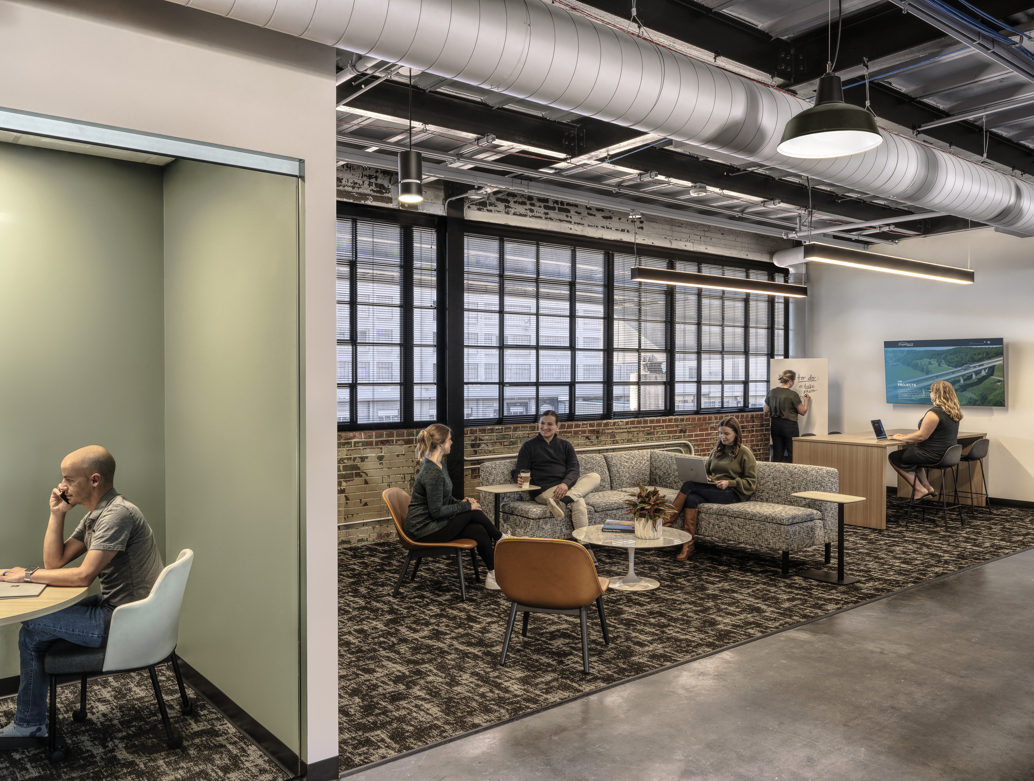 Comfortable welcome are with couches and TV screen next to an enclosed private phone booth at the Lochmueller Group office.