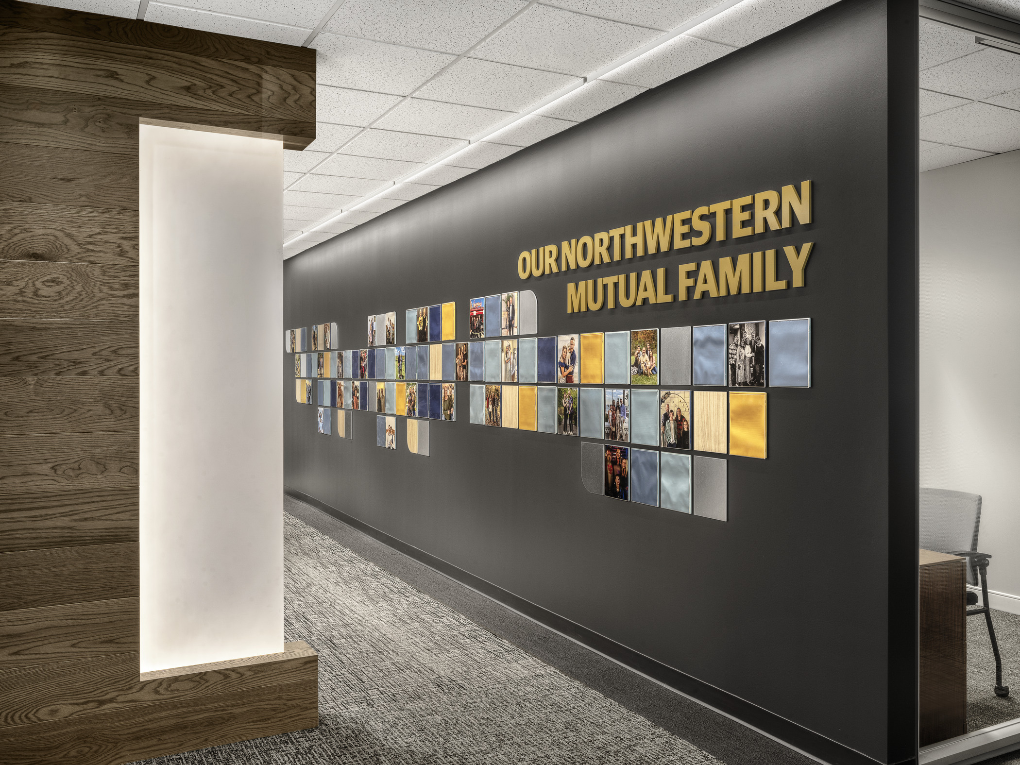 A corporate wall graphic shows a wide variety of family photos from staff of the firm