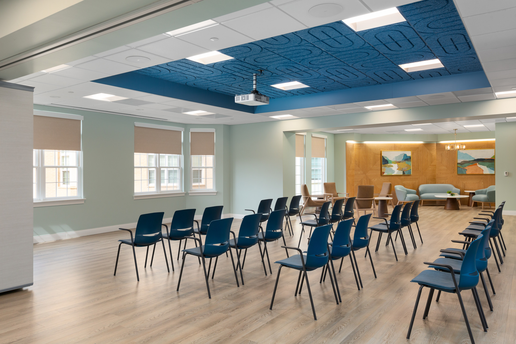 A large multipurpose room featuring embedded acoustic paneling in the ceiling and a coved seating area in the far west side of the room.
