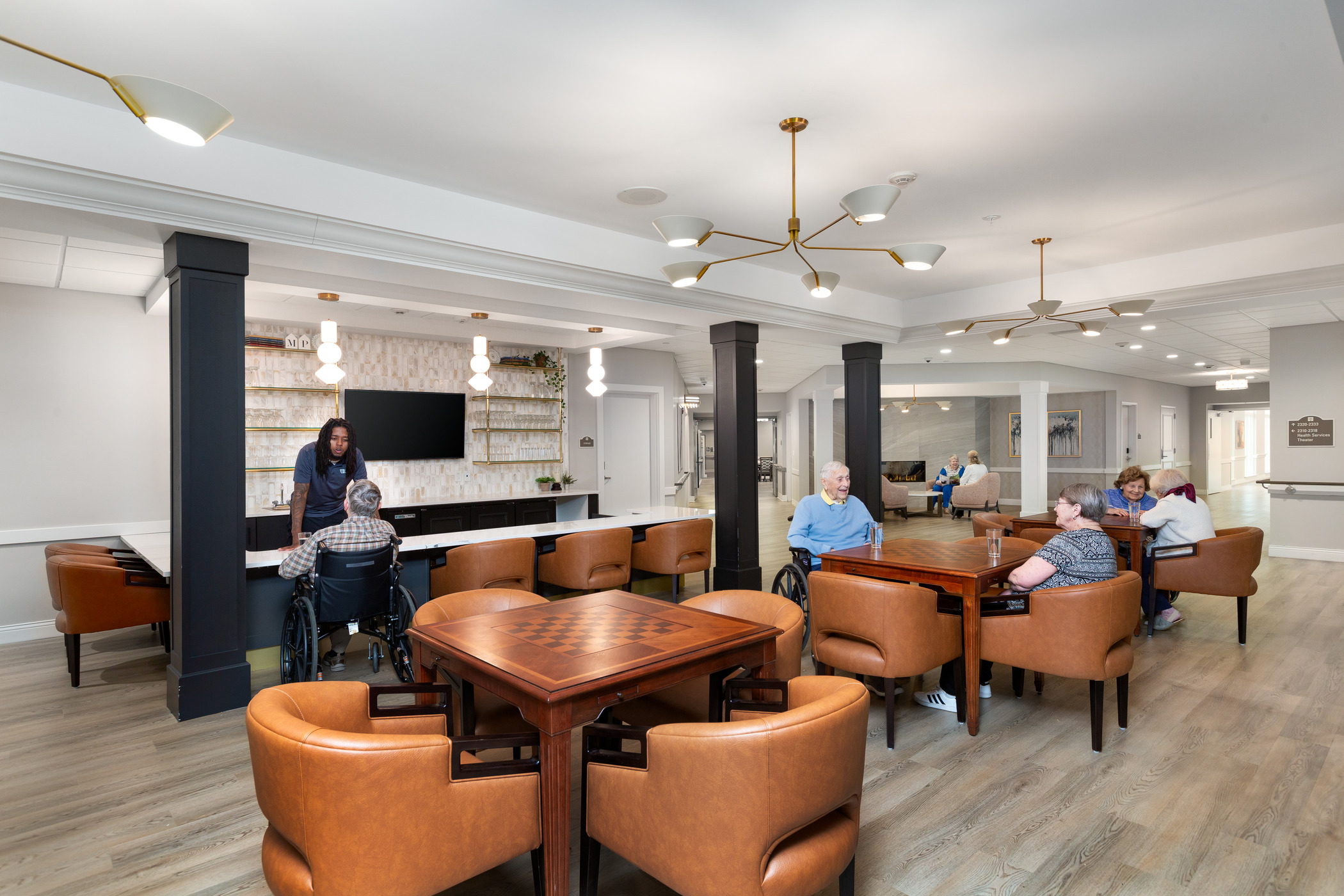 A variety of seniors and staff are photographed in a large common area
