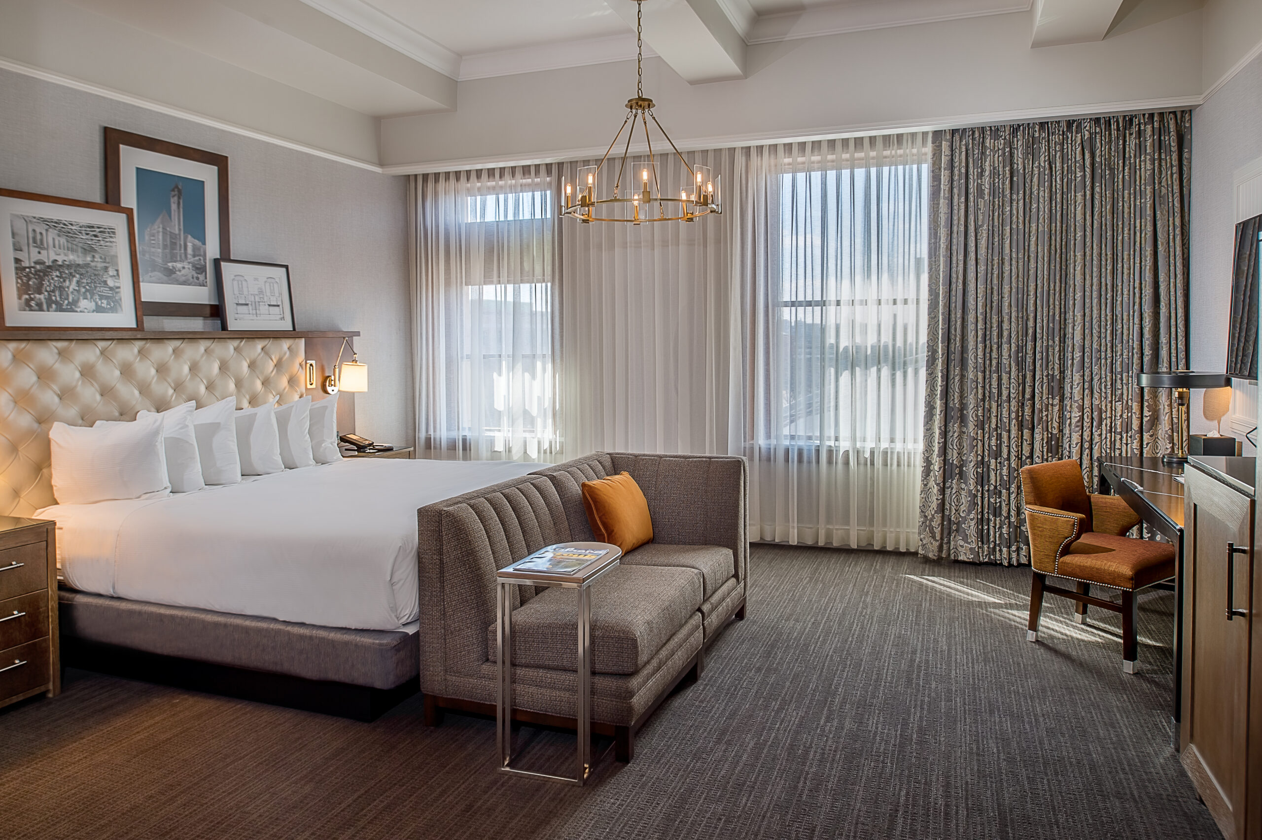 An image of the inside of a hotel room with a bed, desk, chair, and window