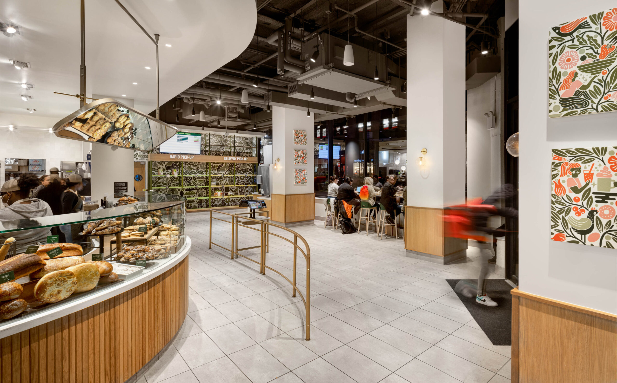 The interior of s tore showing a curved walkway with a railing and a case of food in the background