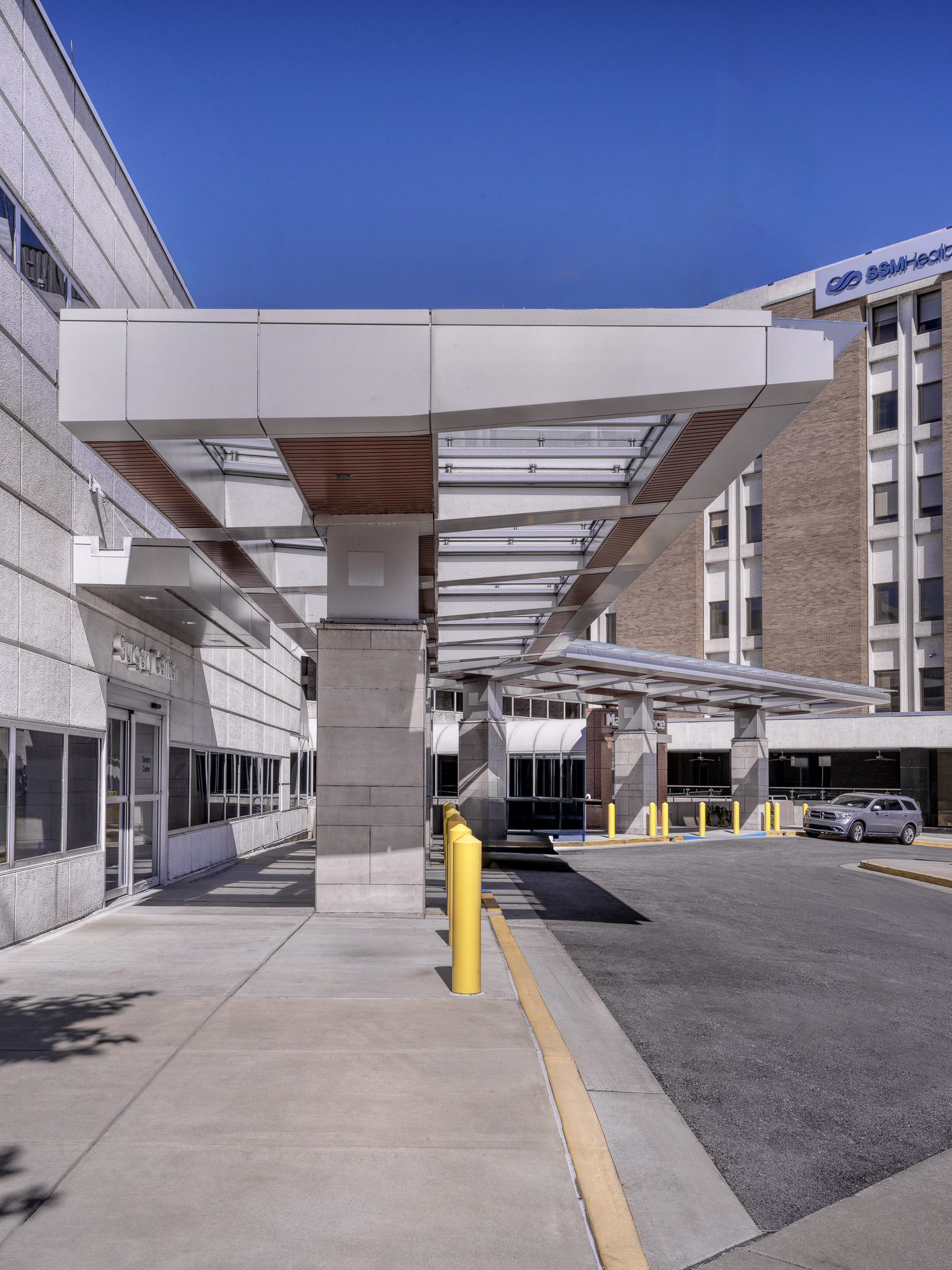 A photograph of a modern canopy structure, connecting two large hospital buildings through a common entrance