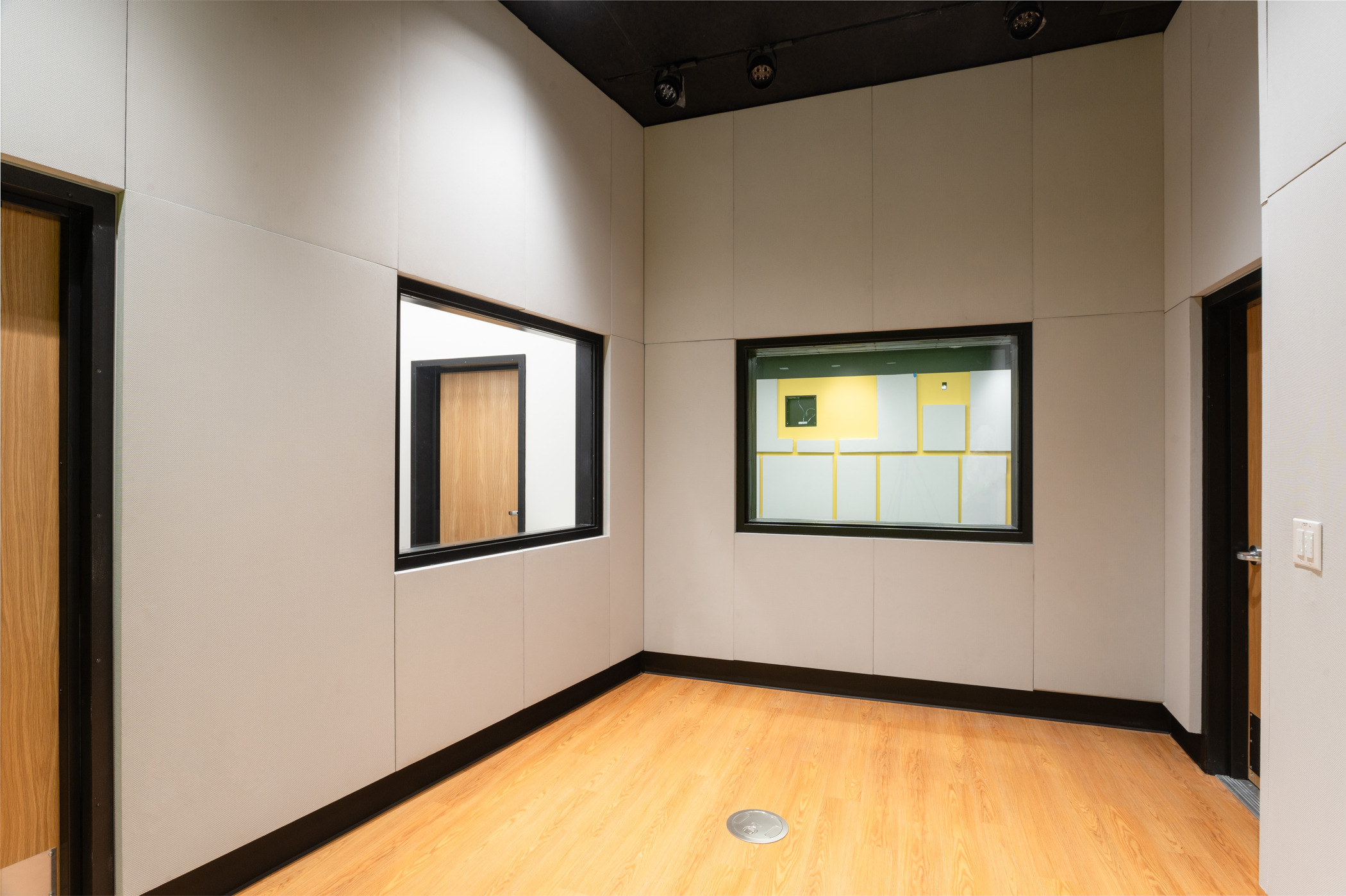 A modern room with white soundproof boards on the wall and wood flooring.