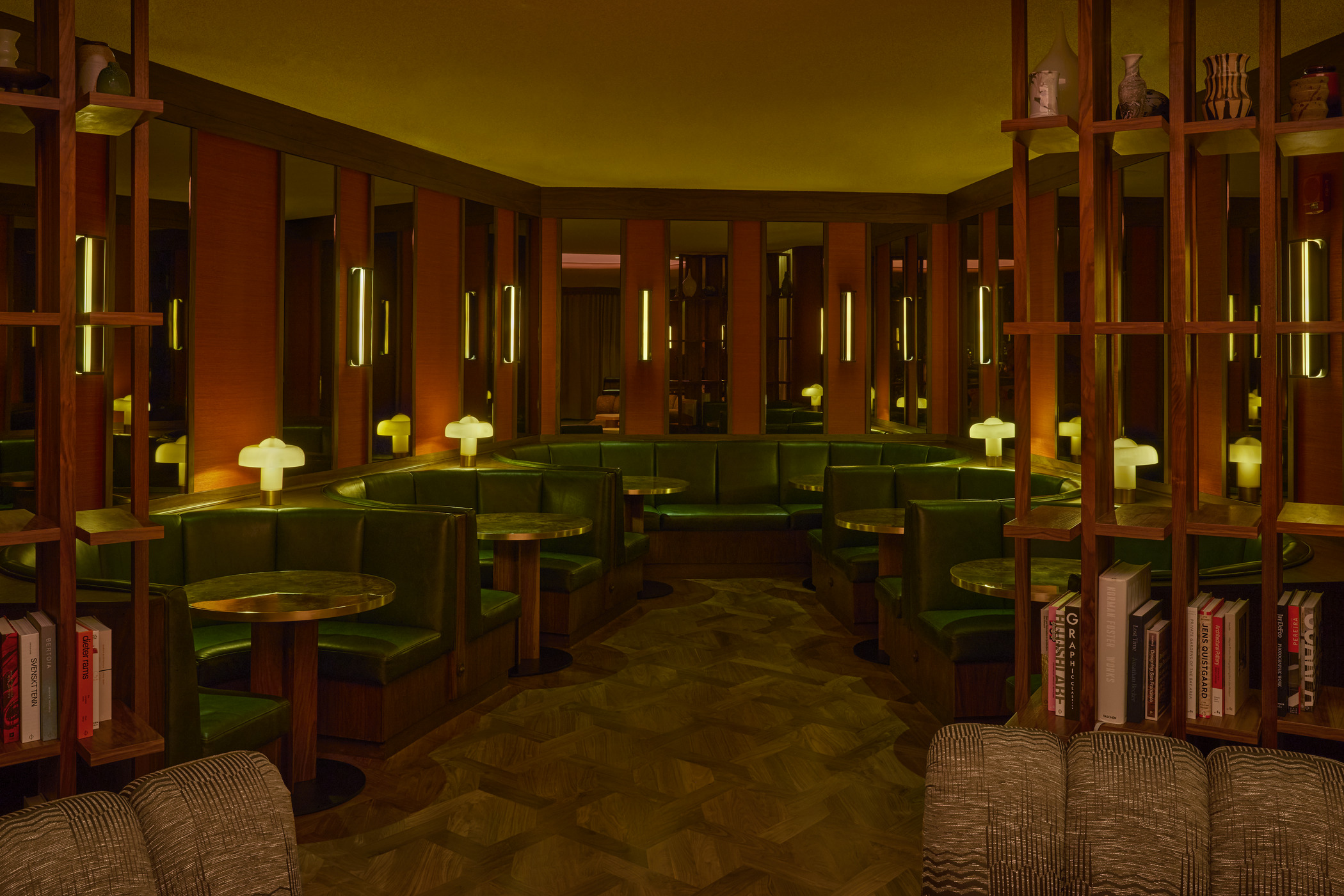 Luxurious restaurant lounge in San Francisco featuring curved seating, round tables, and a dramatic circular ceiling light. Warm wood shelving and ambient lighting create a sophisticated boutique interior design with modern hospitality architecture.