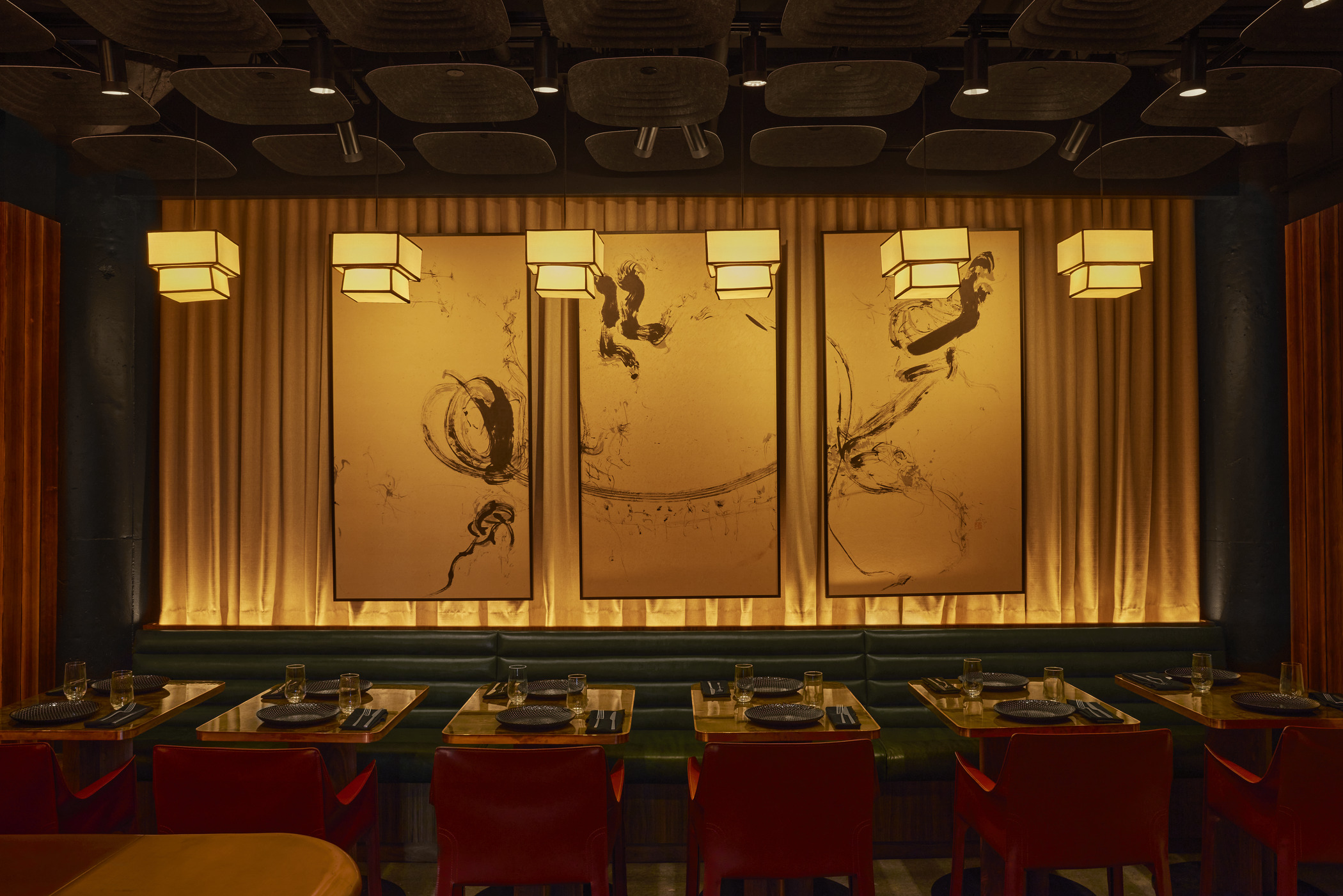 Modern dining space in Ama by Brad Kilgore restaurant featuring large abstract wall art, pendant lights, and red leather chairs. The design blends hospitality architecture with boutique dining aesthetics for a refined upscale experience.