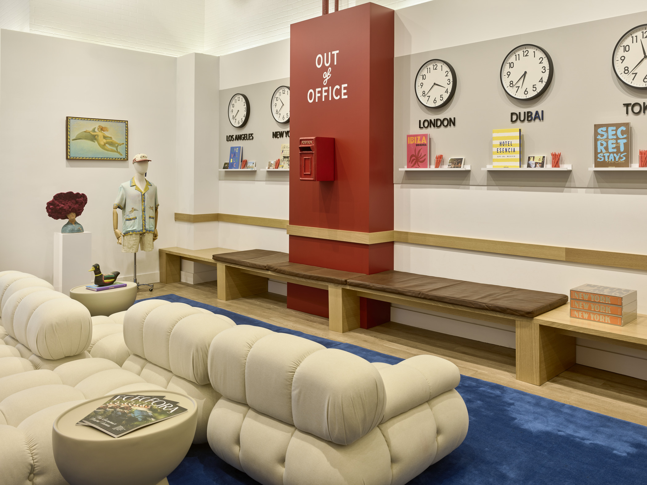 Immersive Fora Travel pop-up lounge with plush white seating, blue rug, global time zone clocks, and bold “Out of Office” feature wall.
