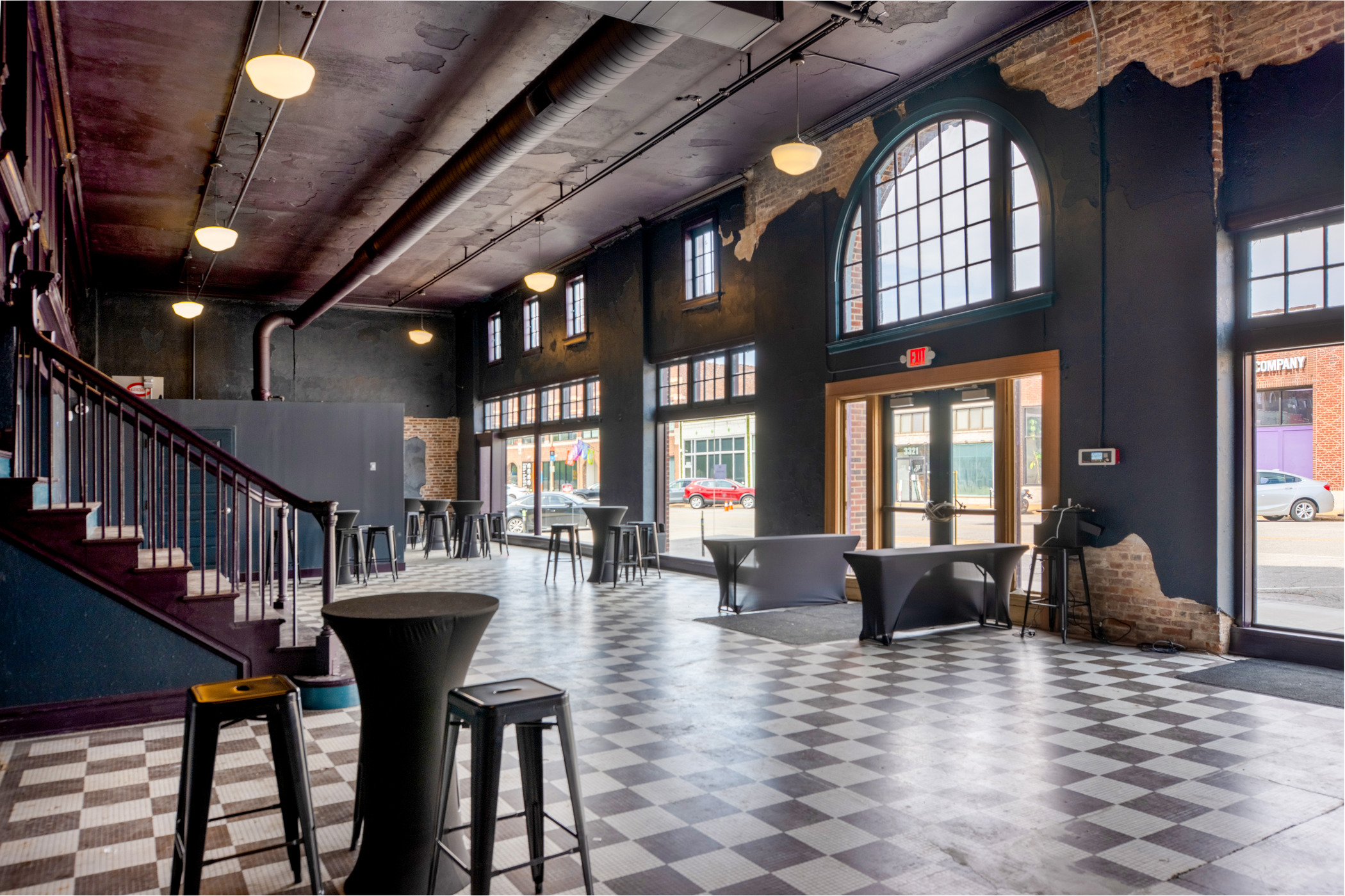 obby of The Sovereign concert venue in St. Louis with black walls, arched windows, exposed brick, and checkered flooring.